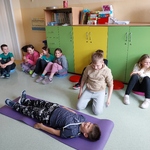 Uczeń układa kolegę w pozycji bocznej bezpiecznej. Reszta uczniów obserwuje