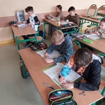 Uczniowie siedzą w ławkach. Wypełniają ćwiczenia