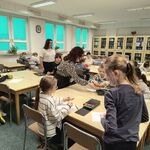 dzieci siedą przy stolikach w bibliotece
