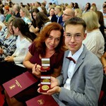 Uczeń i nauczyciel pozują do zdjęcia. Prezentują otrzymane medale.