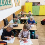 Uczniowie siedzą w ławkach. Kolorują plakaty. 