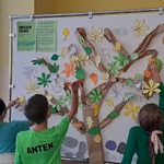 Uczniowie przyczepiają liście do szkolnego drzewa życzliwości
