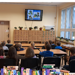 Dzieci siedzą w bibliotece i słuchają bajki