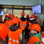 Uczniowie zwiedzają Zakład Unieszkodliwiania Odpadów. Są ubrani w odblaskowe kamizelki i kaski.