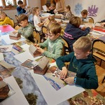 Uczniowie pracują przy prostokątnych stołach. 