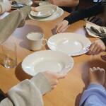 Uczniowie nakrywają do stołu, ustawiając talerze, sztućce i naczynia na drewnianym blacie.
