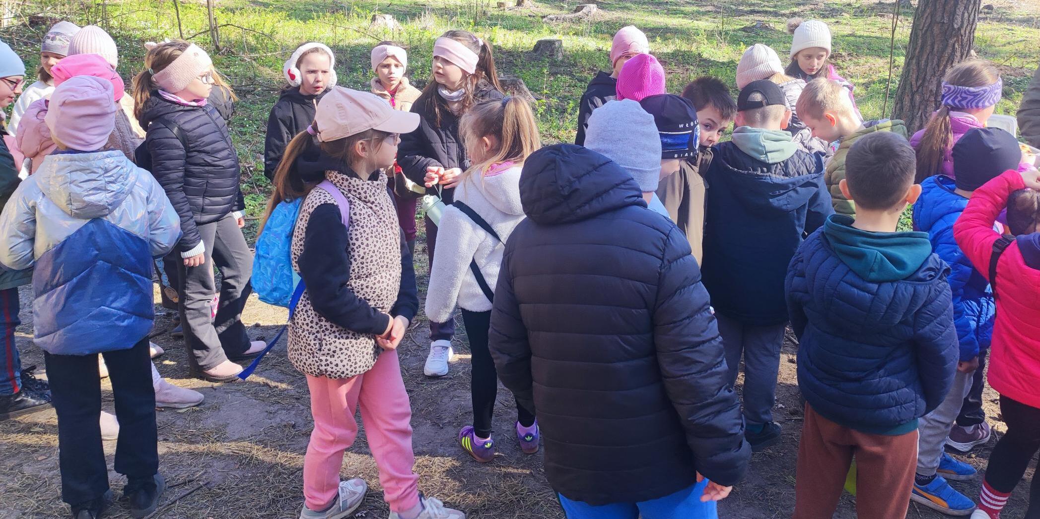 Uczniowie słuchają Pani opowiadającej o pracy leśnika