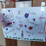 Rysunek ucznia przedstawiający słowa i zwroty w języku angielskim, takie jak „Hi!”, „Listen”, „Thank you!”, „How are you?” i „Bye”, ozdobiony motywami Wielkiej Brytanii, w tym flagą i wieżą Big Ben.