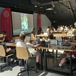 Uczniowie siedzą przy stanowiskach laboratoryjnych i obserwują prezentację doświadczenia wyświetlanego na ekranie.
