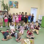 Grupa dzieci w klasie trzyma przed sobą kolorowe kartonowe prace plastyczne z kwiatam