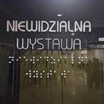 Szklane drzwi z napisem Niewidzialna wystawa oraz opisem w alfabecie Braillea.jpg