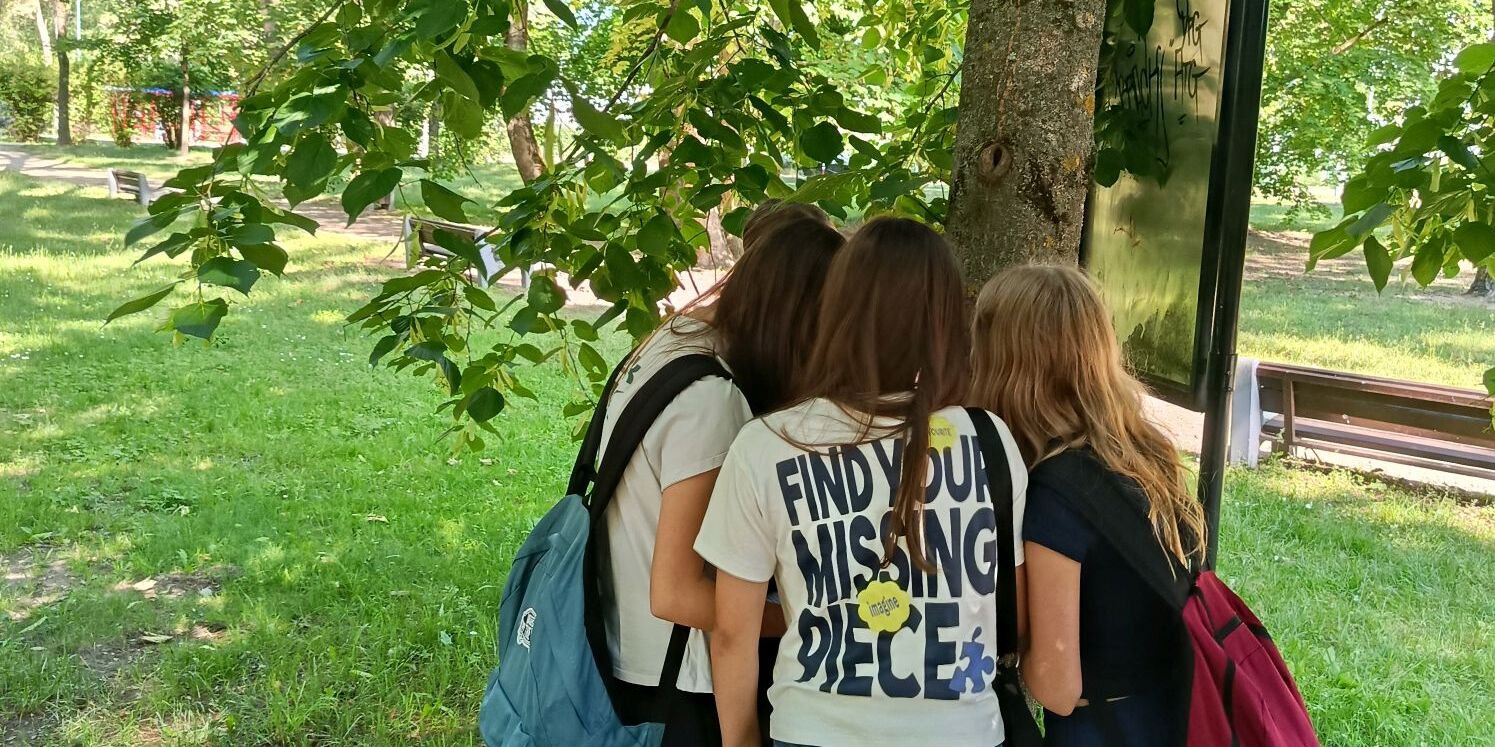 Uczniowie w parku wykonują zadanie z karty pracy