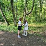 Uczniowie w lesie rozwiązują zadania z karty pracy dotyczące rezerwatu Las Zwierzyniecki