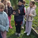 Uczniowie trzymają doniczkę z tują