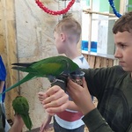 uczeń pozuje do zdjęcia z papugą