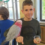 uczeń pozuje do zdjęcia z papugą